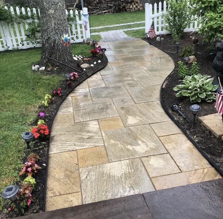 Curved natural-stone walkway winding between garden beds and a mature tree