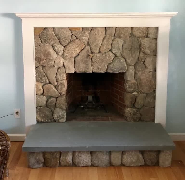 Interior fieldstone fireplace with a slate hearth and white wood mantel