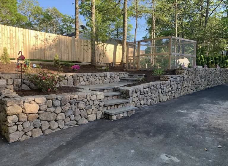 Fieldstone landscape walls with bluestone steps rising between planted beds