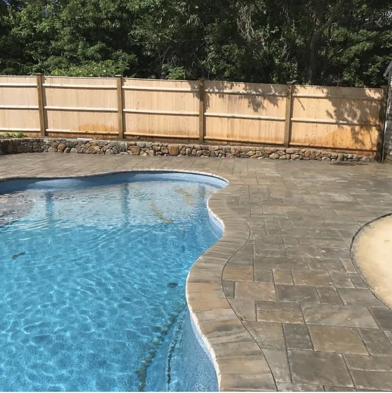 Paver patio and coping following the curved edge of an in-ground pool