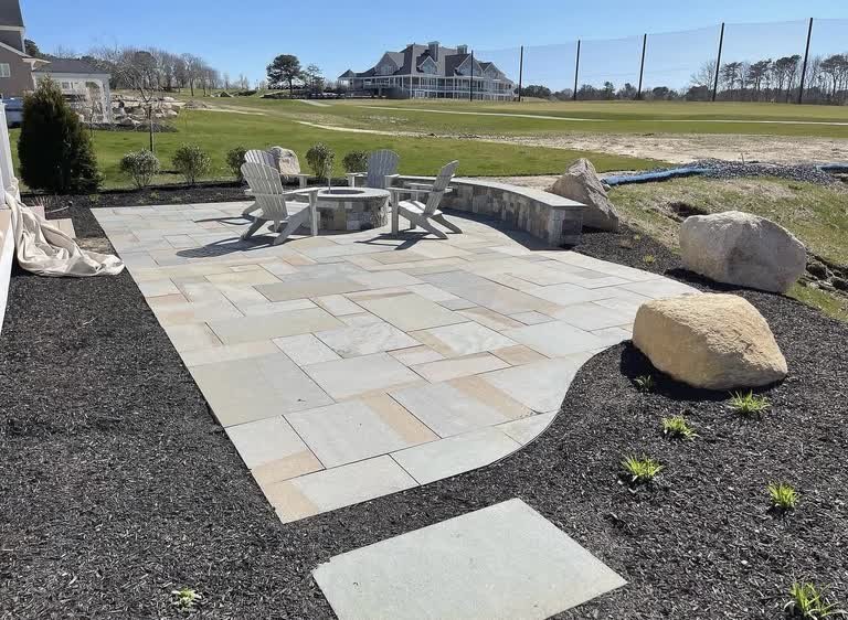Natural-stone patio with a circular fire pit and curved masonry seat wall