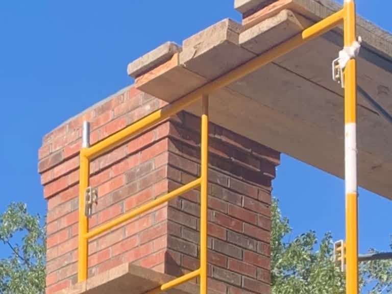 Brick chimney under construction on masonry scaffolding
