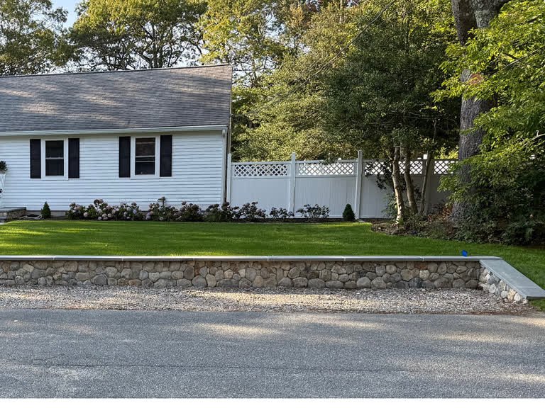 Finished natural-stone landscape wall bordering a lawn