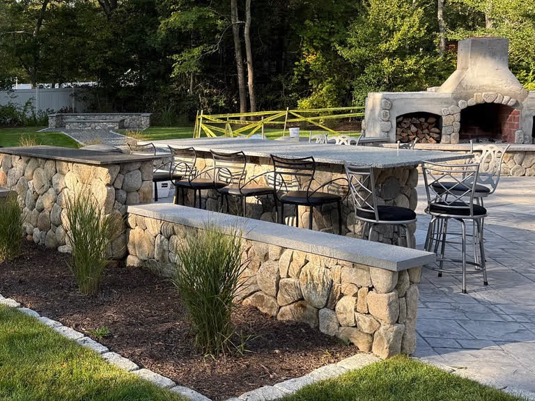 Finished outdoor masonry space with stone counters, walls, patio, and fireplace